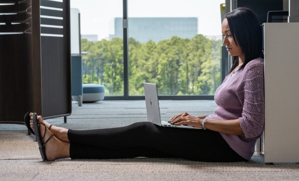 En kvinde, der sidder og arbejder på gulvet med en HP-laptop på skødet.